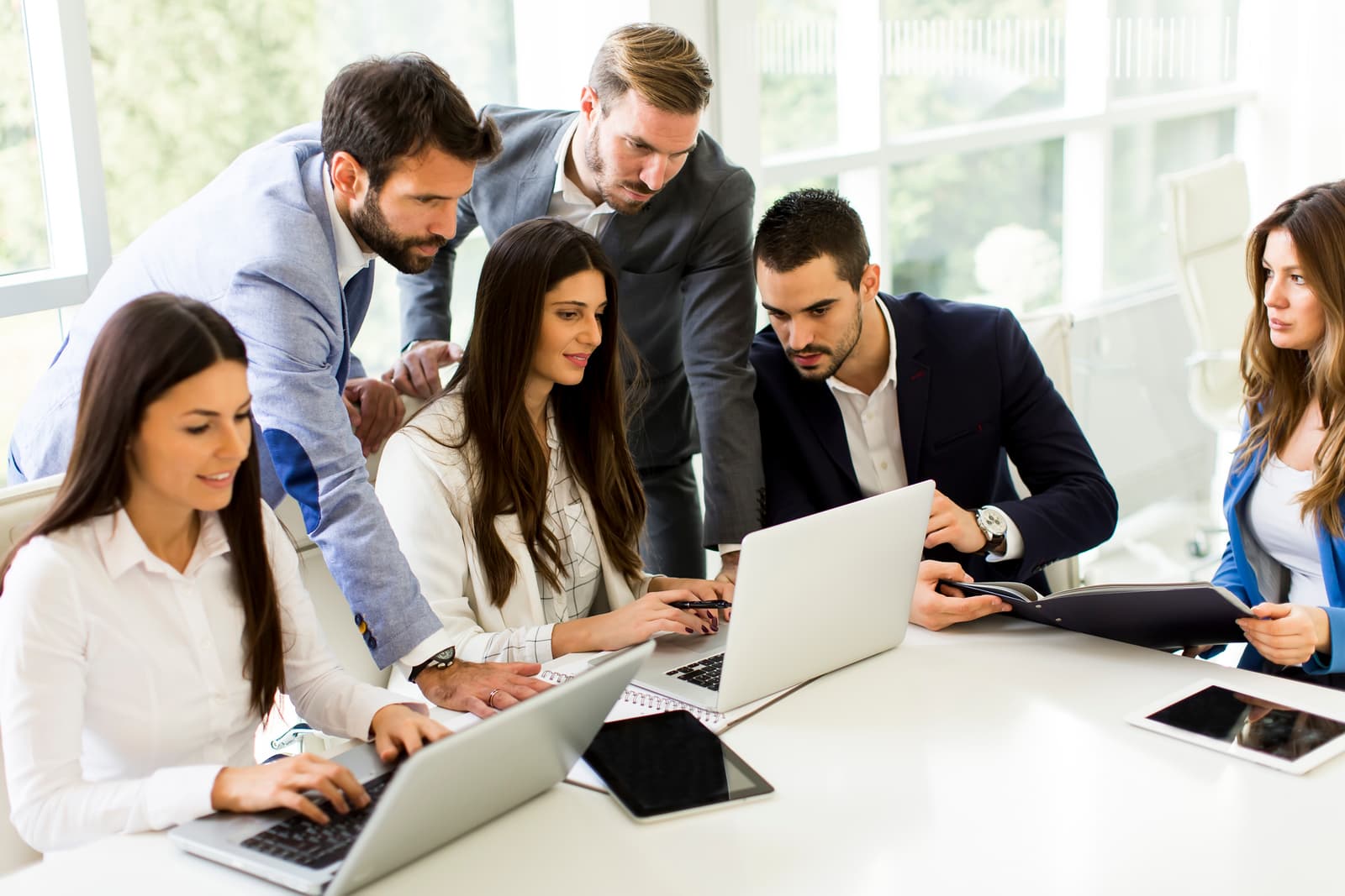 Young business team startup meeting in modern bright office interior working on laptop